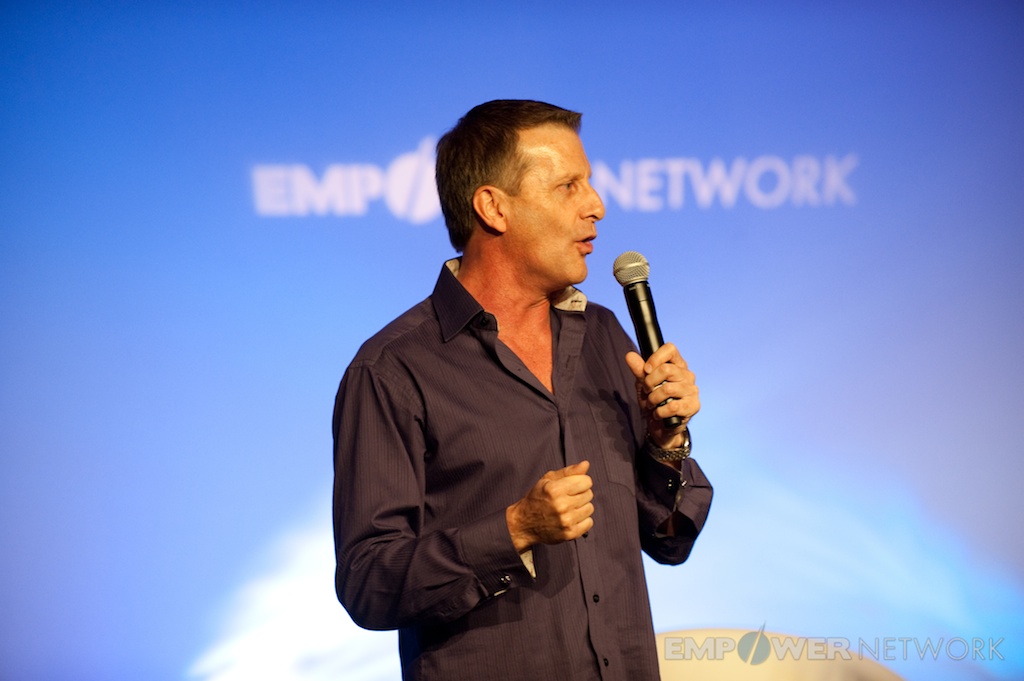 Speaker making a point with microphone in hand in front of the Empower Network backdrop at the 2012 Atlanta event