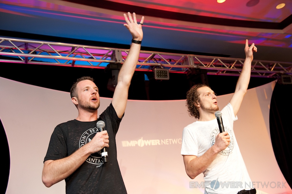 Two speakers with arms raised rallying the crowd from stage at Empower Network's 2012 Atlanta event