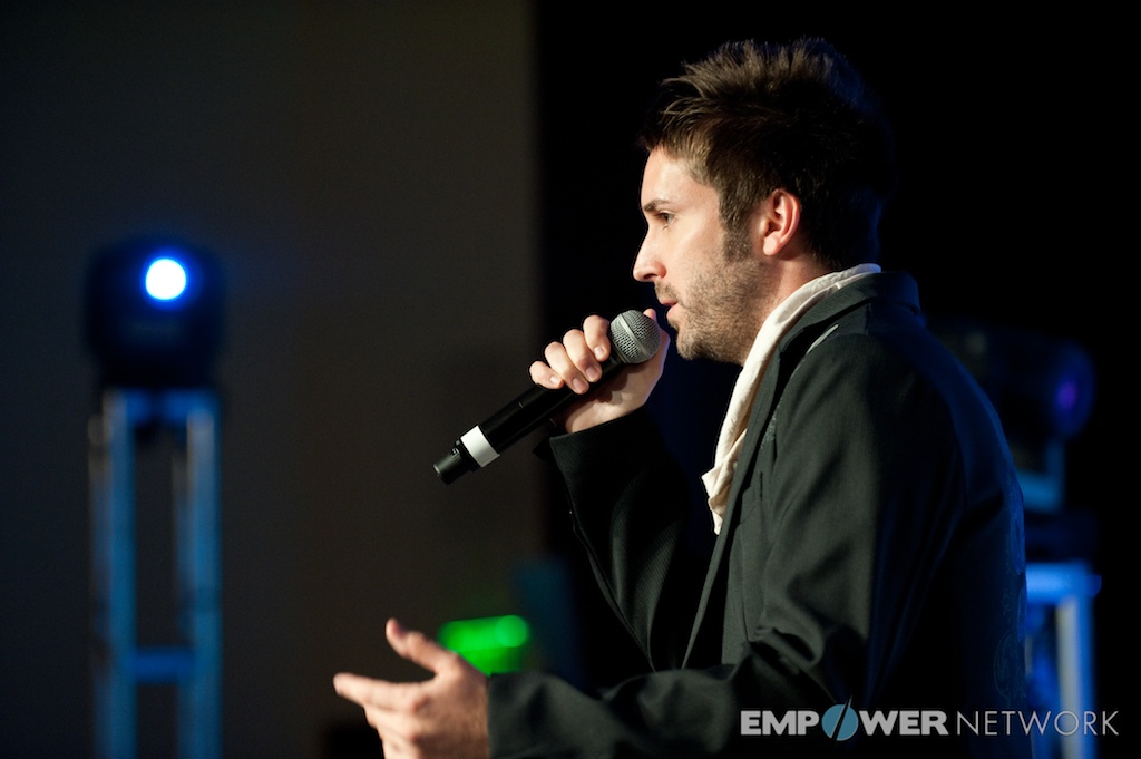 Dramatic profile of a performer with microphone under dark stage lighting at Empower Network's 2012 Atlanta event
