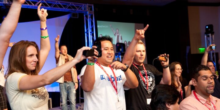 Attendees cheering with fists and phones in the air near the stage at Empower Network's 2012 Atlanta event