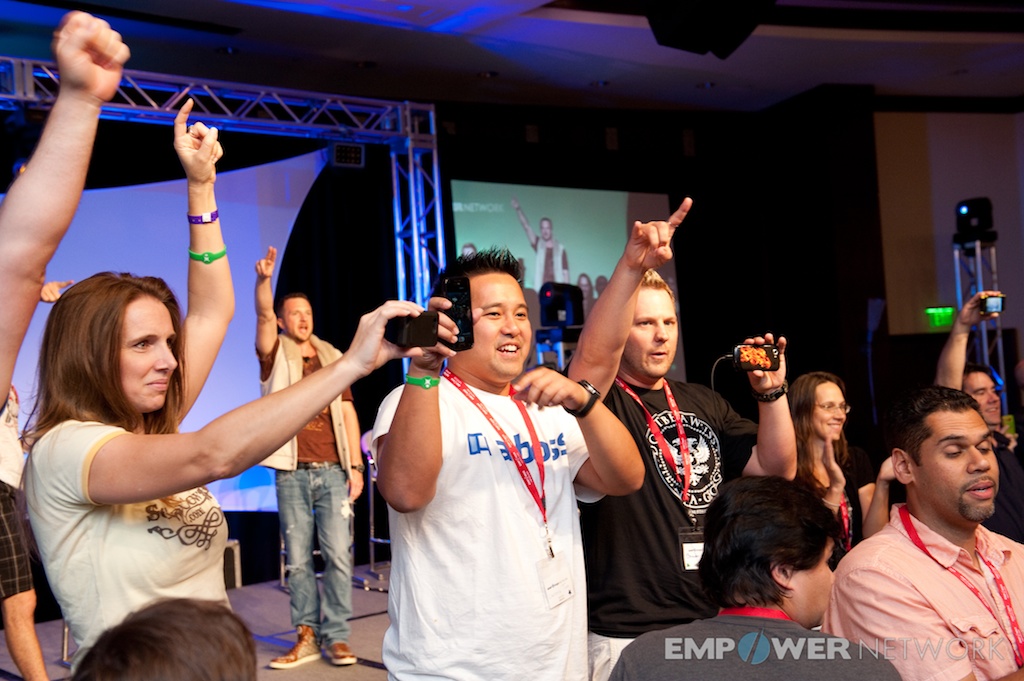 Attendees cheering with fists and phones in the air near the stage at Empower Network's 2012 Atlanta event