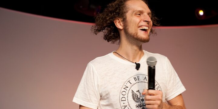 Speaker laughing mid-talk with microphone in hand on stage at Empower Network's 2012 Atlanta event