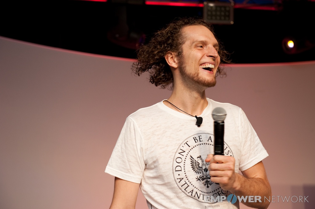Speaker laughing mid-talk with microphone in hand on stage at Empower Network's 2012 Atlanta event