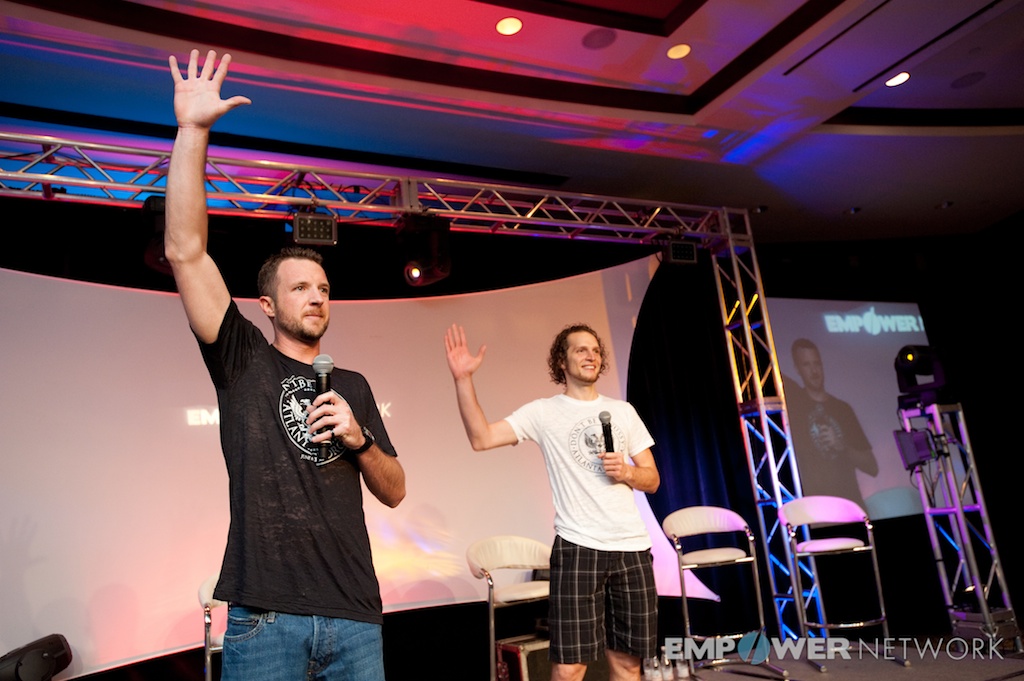 Two speakers waving with hands raised high on a colorfully lit stage at Empower Network's 2012 Atlanta event