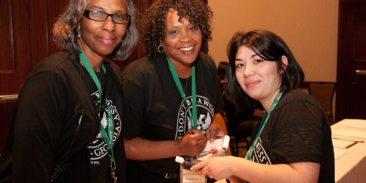 Three volunteers smiling together at the registration table at Empower Network's 2012 Atlanta event