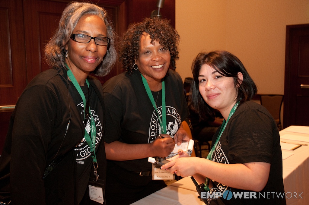 Three volunteers smiling together at the registration table at Empower Network's 2012 Atlanta event