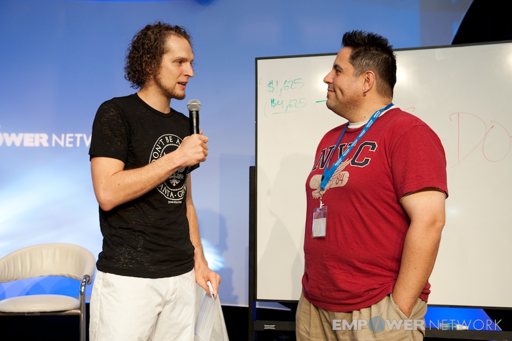 Speaker in conversation with an attendee beside a whiteboard on stage at Empower Network's 2012 Atlanta event