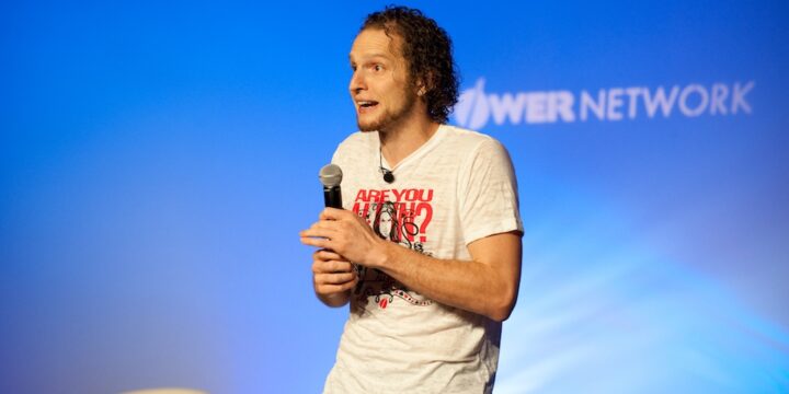 Speaker with microphone against a blue-lit Empower Network stage backdrop at the 2012 Atlanta event