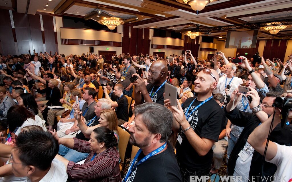 Energized crowd standing and raising cameras in the ballroom at Empower Network's 2012 Atlanta event