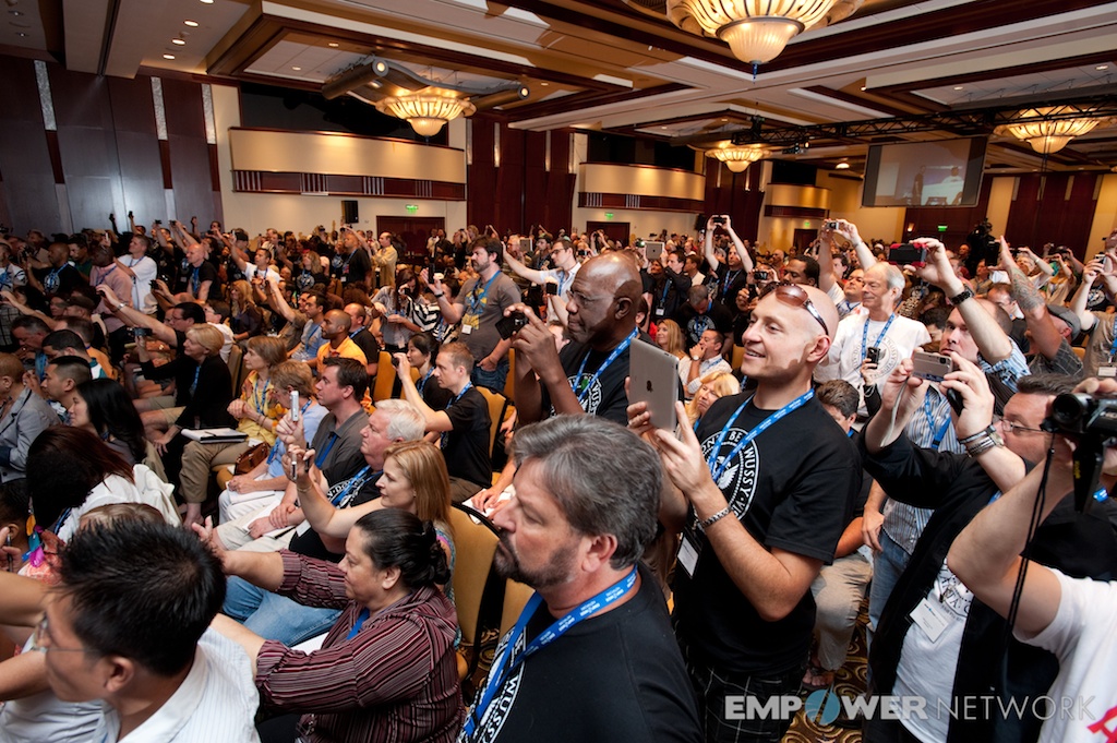 Energized crowd standing and raising cameras in the ballroom at Empower Network's 2012 Atlanta event